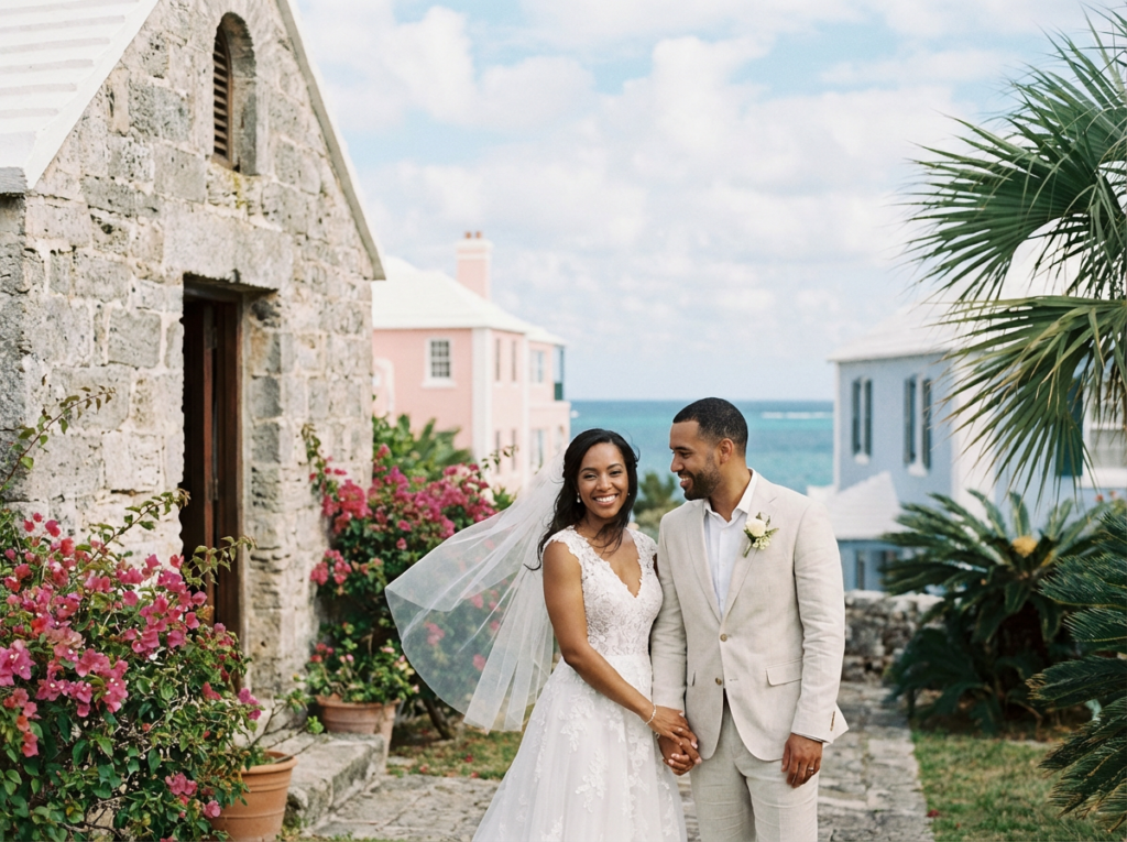 Bride and groom outside a Bermuda stone chapel with lush gardens and blue ocean views